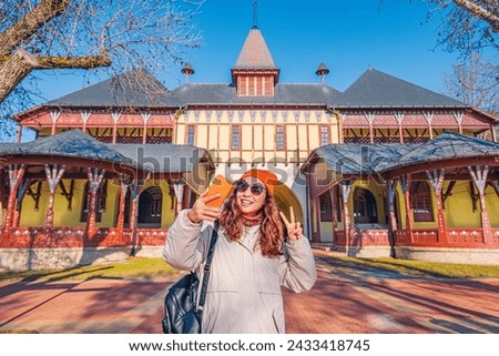 Tourist girl taking selfie photos on her smartphone against buildings on Palic lake, while travelling in Serbia
