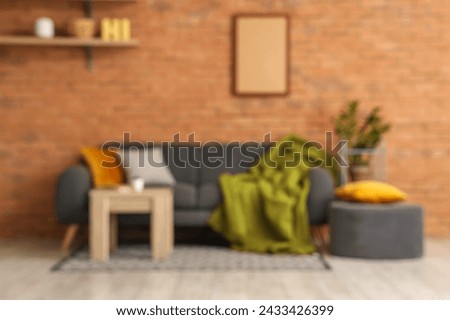 Loft style interior of living room with cozy sofa, pouf and table, blurred view
