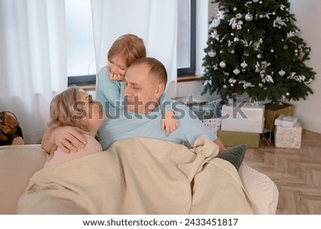 Portrait of a happy young family. Happy family mother, father, little daughters . A happy young family spends time together in a home interior. Mom and dad kiss their kids