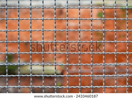 metallic border separation fence and the brick wall of the penitentiary out of focus in the background Royalty-Free Stock Photo #2433460187