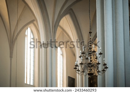 Chandelier with modern lightbulbs inside a gothic church with tall roof and concrete pillars. Beautiful church with ornaments.