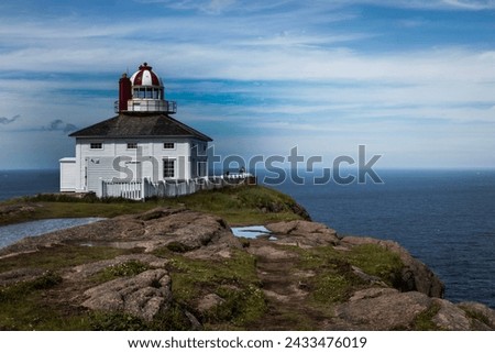 Light house on coast with ocean behind clouds behind light house 
