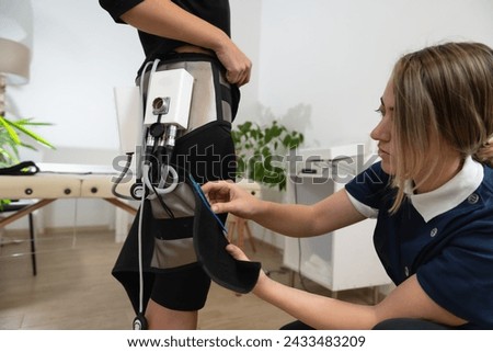 Electro-stim EMS therapy for sculpting legs. Salon therapist utilizes electrodes to focus on enhancing the leg contours for weight management.

