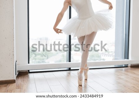 Cropped view of lags of beautiful graceful ballerina in white swan dress. Young ballet dancer practicing before performance in black tutu, classical dance studio, copy space.