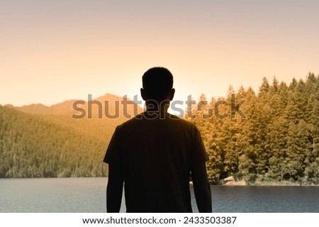 Traveler Young Man Standing in Summer Mountain Lake at Sunset and Enjoying View of Nature