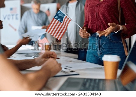 Close up of African American female voter talking to a volunteer at polling place during US elections. Royalty-Free Stock Photo #2433504143