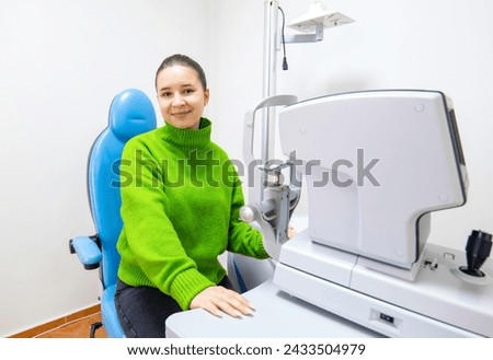 a woman in a green sweater is sitting in a blue chair in front of a machine