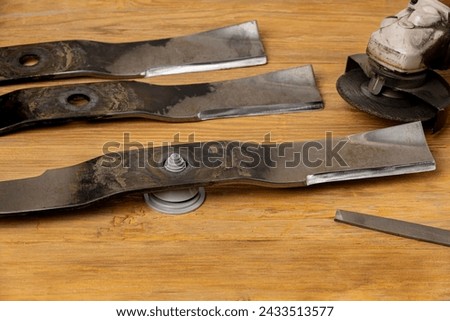 Sharpening and balancing dull lawnmower blades. Lawn mower equipment maintenance, repair and service concept. Royalty-Free Stock Photo #2433513577