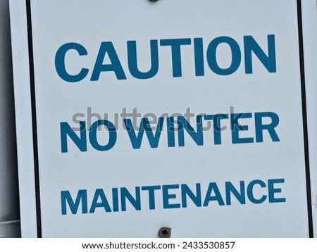 A closeup of a caution no winter maintenance sign.