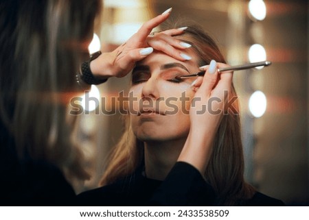 
Professional Makeup Artist Applying Eyeshadow on a Model. Woman having her looks changed through professional makeup
