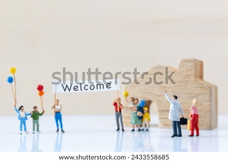 Miniature people holding "Welcome" signs at front of the home and copy space for text.