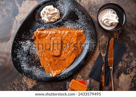 Lotus Crepe cookie with whipped cream, knife and fork served in dish isolated on dark background closeup top view of cafe baked dessert food