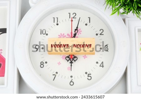 Willy - nilly latin expression volens-nolens (willing or unwilling) written on the wooden blocks on the clock with hands