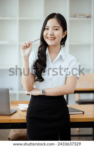 Happy young Asian woman relax standing on desk search and do job in internet in office.