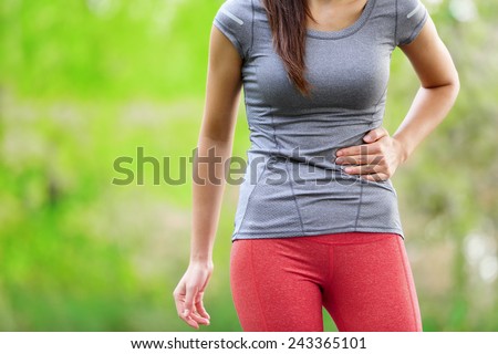 Side stitch - woman runner side cramps after running. Jogging woman with stomach side pain after jogging work out. Female athlete. Royalty-Free Stock Photo #243365101