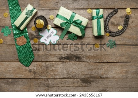 Gift boxes with tie, pot of golden coins and horseshoe for St. Patrick's Day celebration on wooden background