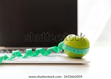 Close up green apple and tape measure.  Healthy snack for diet planning for working in office.  Fresh fruit dumbbell and laptop background.  Healthy Lifestyle Concept
