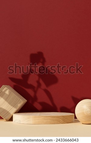 Wooden scenes of different geometric shapes on an abstract red and beige background with the shadow of plant leaves. Premium empty podium for advertising and presentation your product. Showcase.