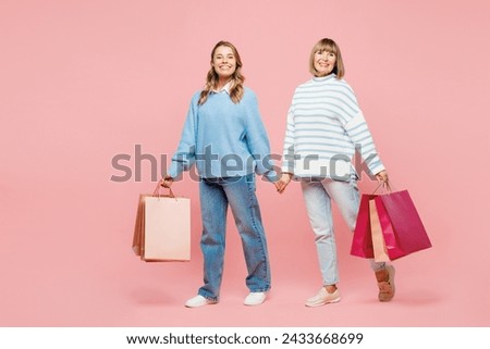 Full body elder parent mom young adult daughter two women together wear blue casual clothes hold paper package bags after shopping isolated on plain pink background Black Friday sale buy day concept