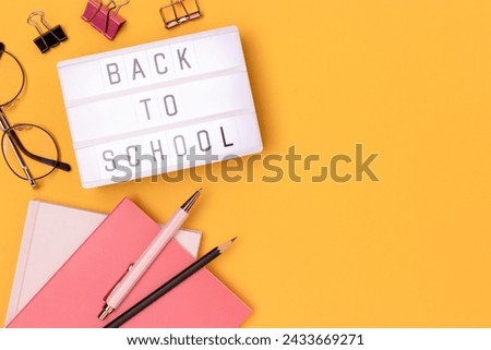 Back to school. Lightbox with letters and stationery on a yellow background. Concept with copy space.