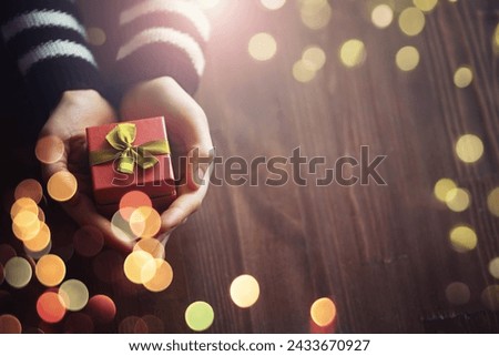 Top view of male and female hands holding gift box with golden ribbon on pink background Flat lay. Present for birthday, valentine day, Christmas, New Year. Congratulations background copy space.