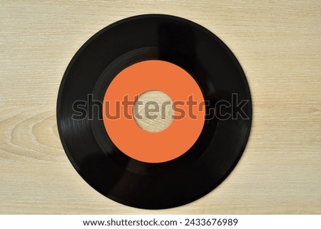 45 rpm old vinyl record on the brown wooden table. Vintage technology concept. Top view.