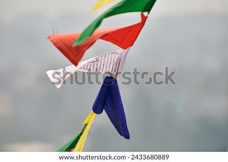 Colorful Tibetan prayer flags on blurred Kathmandu cityscape background symbolizing cultural value and spiritual heritage of Nepali region, connection between earthly and spiritual realms