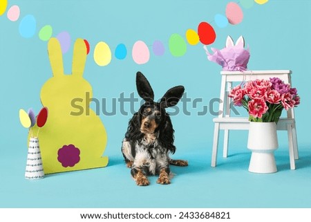 Cute cocker spaniel in bunny ears with beautiful tulips, Easter paper eggs and rabbit on blue background