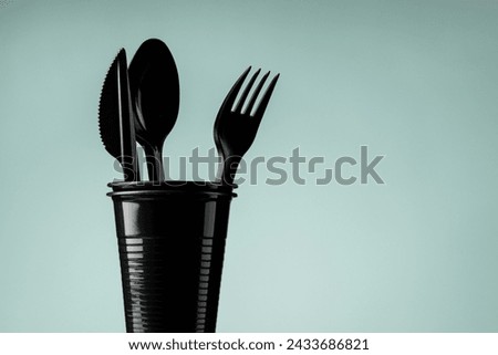 Disposable black plastic cup and cutlery on a gray background. Ecology and recycling concept. Royalty-Free Stock Photo #2433686821
