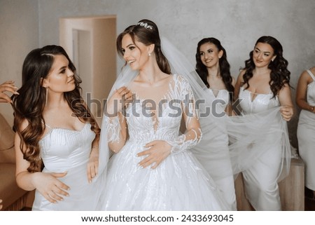 Bridesmaids rejoice in the morning, helping to fasten the buttons on the wedding dress and prepare for the wedding ceremony. They take pictures, smile, help the bride with her shoes.