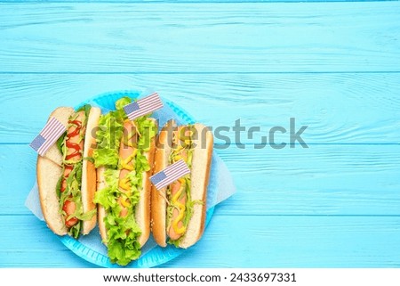 Plate with tasty hot dogs for Memorial Day celebration on color wooden background