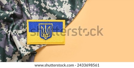 Military badge of Ukrainian army with trident and soldier's uniform on beige background with space for text