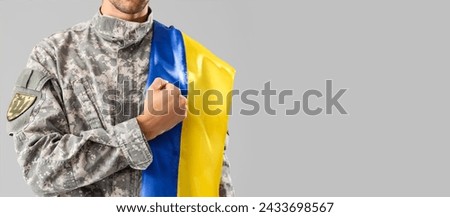Male soldier with Ukrainian flag on grey background with space for text