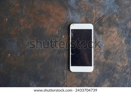 White phone with a broken screen on dark background