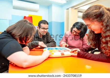 Group of disabled people playing board games together having fun in a day center for people with special needs Royalty-Free Stock Photo #2433708119