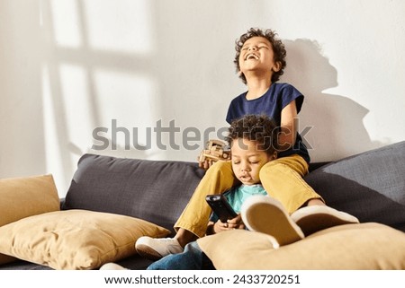 cheerful african american little brothers playing with car toy and watching TV in living room