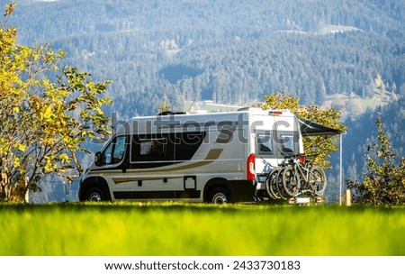 Campervan or motorhome with bicycle rack parked in the nature countryside. Camper van or  motor home is camping in a meadow surrounded by forest and hills. Active family vacation in Slovenia. Royalty-Free Stock Photo #2433730183