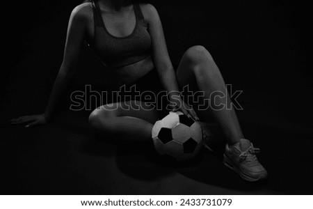 A beautiful slender girl athlete in shorts and a top plays football
