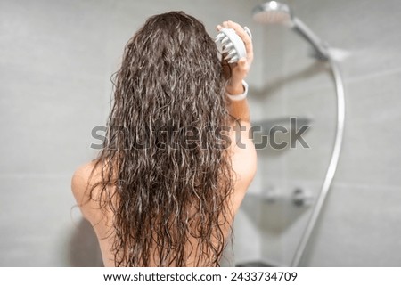 Young woman doing self hair scalp massage with scalp massager or hair brush for hair growth stimulating at home bathroom. High quality photo