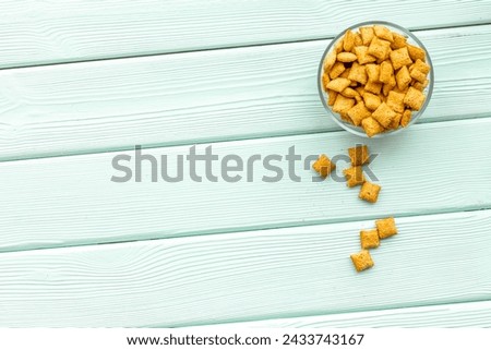 Healthy breakfast. Puffins, corn cereals in bowls on mint green wooden background top view space for text