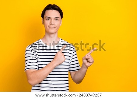Portrait of handsome student wear stylish t-shirt indicating at proposition empty space isolated on bright yellow color background