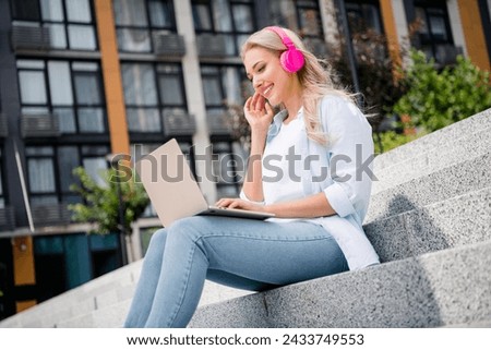 Photo of cheerful cute lovely woman spending free time after lessons outdoors chatting on netbook macbook outdoors