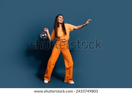 Full length photo of brunette charming model girl with disco ball makes rhythm dynamic dance moves isolated on dark blue color background