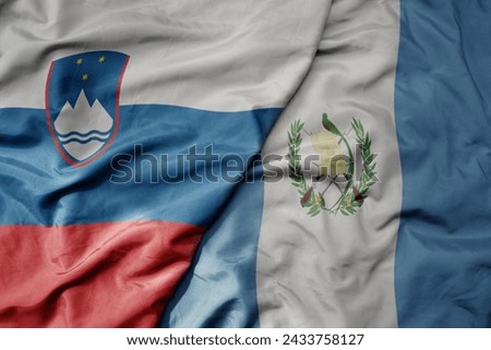 big waving national colorful flag of guatemala and national flag of slovenia. macro
