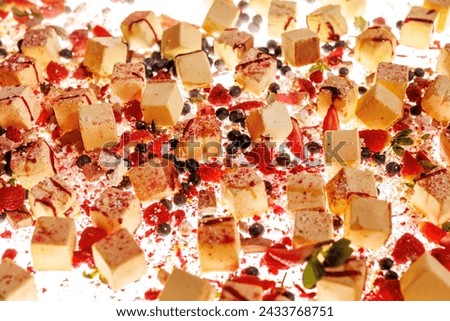 The set of bite-sized small cheesecakes on a white surface. Berries, sugar powder, and chocolate are used as decor Royalty-Free Stock Photo #2433768751