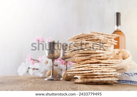 Passover celebration concept. Matzah, red kosher and walnut on wooden vintage table in front of spring blossom tree garden and flowers landscape with sun rays with copy space. Mock up.