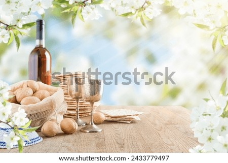 Passover celebration concept. Matzah, red kosher and walnut on wooden vintage table table in front of spring blossom tree garden and flowers landscape with sun rays with copy space. Mock up. Royalty-Free Stock Photo #2433779497