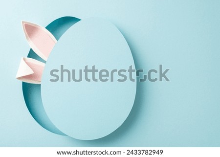 Artistic Easter theme, featuring top view of whimsical bunny ears emerging from egg-like opening with detachable cover, arranged on pastel blue surface, with space for personalized promo content Royalty-Free Stock Photo #2433782949