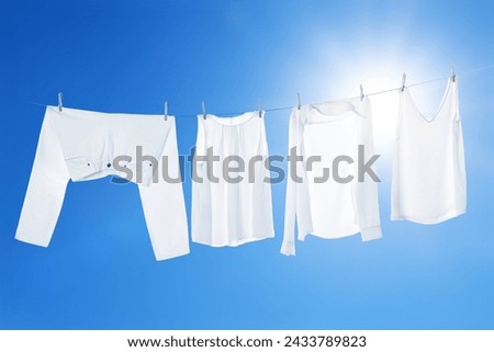 Different clothes drying on washing line against blue sky Royalty-Free Stock Photo #2433789823
