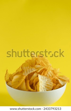 Close-up of cassava chips or crisps in bowl against yellow background. perfect for recipes, articles, catalogues, or commercials